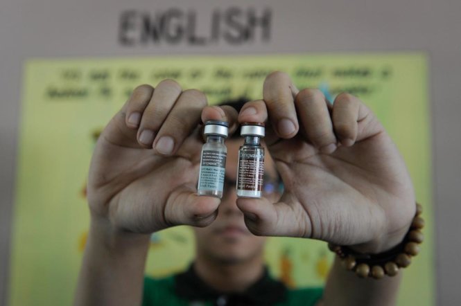Một nhân viên y tá đang cầm hai lọ vắc xin Dengvaxia, vắc xin phòng sốt xuất huyết đầu tiên trên thế giới, tại Manila ngày 4-4-2016 - Ảnh: Getty Images