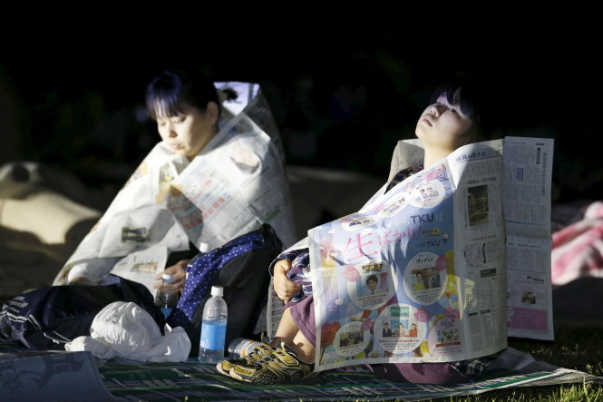 Các nạn nhân phải dùng giấy báo để giữ ấm sau khi chạy vào khuôn viên Trường đại học Kumamoto để đảm bảo an toàn 
- Ảnh: Reuters