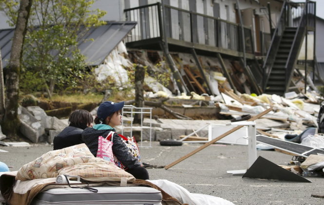 Một sinh viên đại học tại thị trấn Minamiaso, tỉnh Kumamoto ngồi nghỉ mệt bên ngoài ký túc xá tan hoang sau trận động đất - Ảnh: Reuters