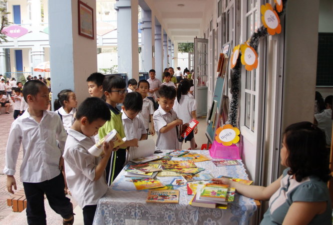Các em học sinh trường tiểu học Bạch Mai chọn mua sách từ gian hàng NXB Kim Đồng - Ảnh: Đức Triết