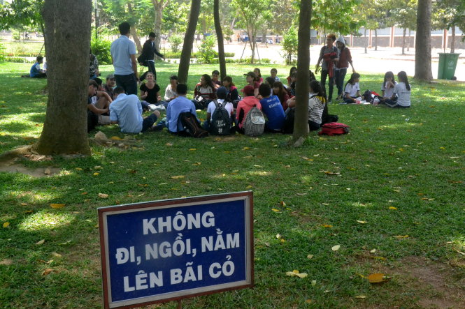 Cả bạn trẻ VN, nước ngoài vô tư ngồi trên cỏ, nơi có biển cấm. Ảnh chụp trong khuôn viên Trường ĐH Sư phạm kỹ thuật TP.HCM sáng 19-4 - Ảnh: Quang Phương