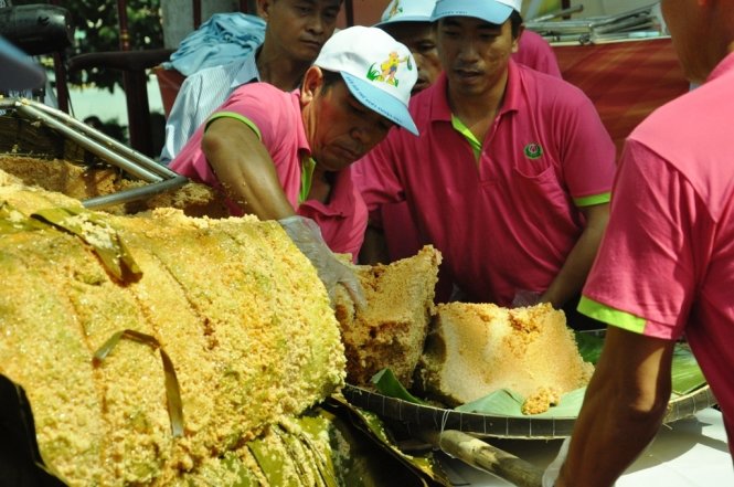 Chiếc bánh chưng khổng lồ được các nhân viên công viên văn hóa Đầm Sen dùng tay bốc, chia nhỏ cho người dân - Ảnh: Hồng Lam