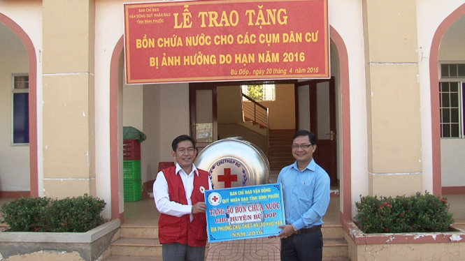Ông Nguyễn Tấn Hưng trao bảng tặng bồn nước cho lãnh đạo huyện Bù Đốp - Ảnh: B.L