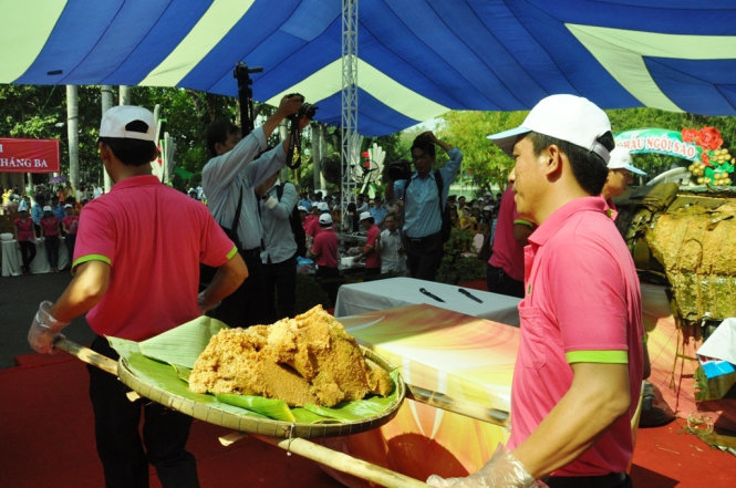 Bánh chưng khủng được nhân viên công viên văn hóa Đầm Sen phân nhỏ và chia cho người dân - Ảnh: H.Lam