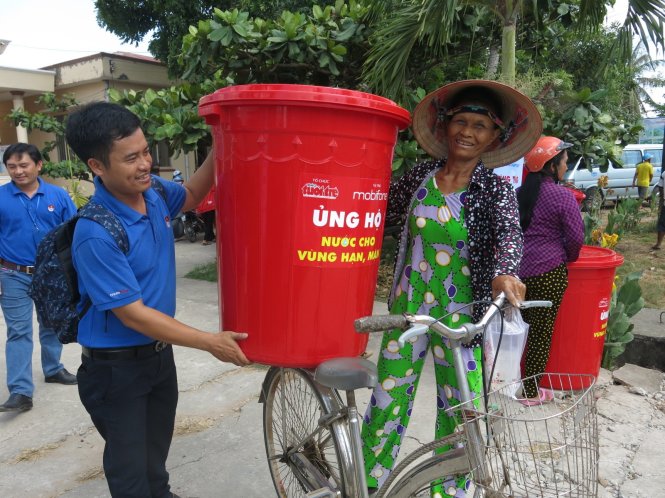 Đoàn viên thanh niên giúp đỡ đưa thùng chứa nước lên xe cho bà con  - Ảnh: T.Trang