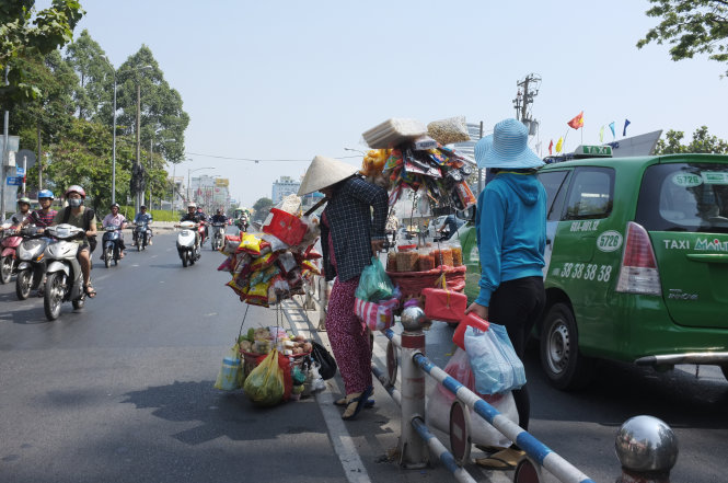 Một người bán hàng rong cố trèo qua dải phân cách trên đường Nguyễn Thị Minh Khai, Q.1, TP.HCM - Ảnh: Hoài Linh