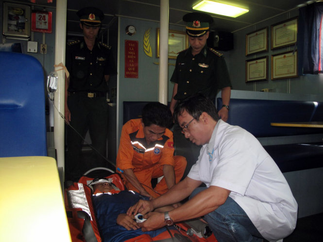 Bác sĩ Ngô Diên Anh Tuấn, Trung tâm Y tế 115 Đà Nẵng đang sơ cứu cho ngư dân trên tàu - Ảnh: N.TRẦN