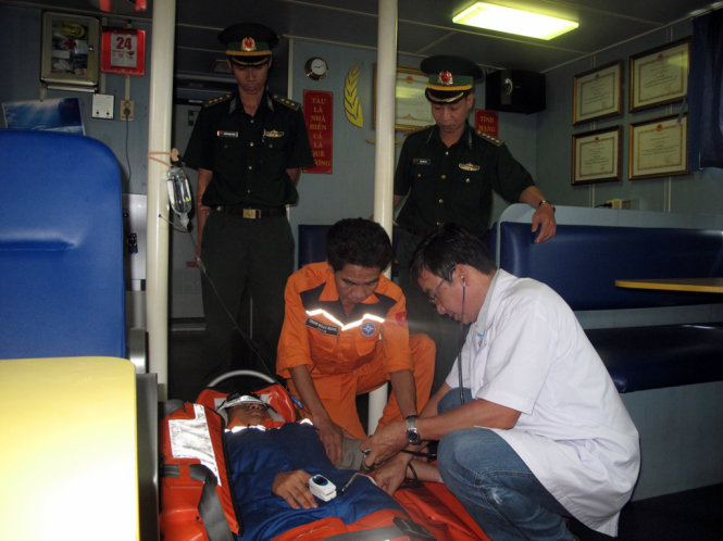 Bác sĩ Ngô Diên Anh Tuấn, Trung tâm Y tế 115 Đà Nẵng đang sơ cứu cho ngư dân trên tàu - Ảnh: N.TRẦN