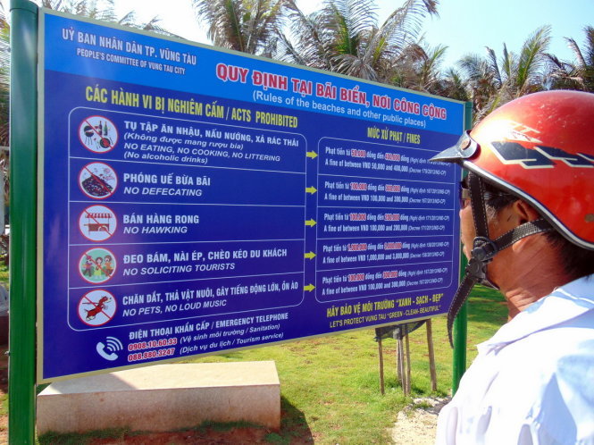 Một người dân đọc bảng thông báo cấm ăn nhậu, xả rác, nấu nướng dưới bãi tắm của UBND TP Vũng Tàu chiều 26-4 - Ảnh: Đông Hà