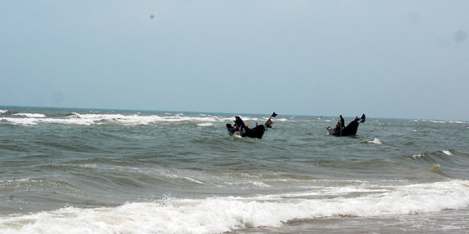 Hai chiếc thuyền thành một tổ thả lưới chỉ cách bờ vài mét - Ảnh: Quốc Nam