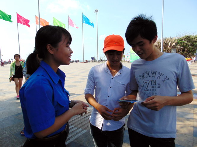 Đoàn viên thanh niên Vũng Tàu phát cẩm nang du lịch cho du khách và vận động họ không xả rác tại bãi tắm - Ảnh: Đông Hà