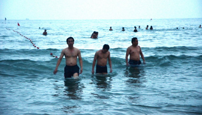 Ông Trần Chí Cường - phó giám đốc Sở VH-TT&DL Đà Nẵng (bìa phải) tắm biển chiều 29-4 - Ảnh: B.Q