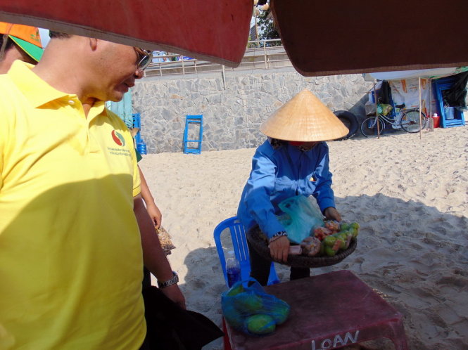Ông Mai Ngọc Thuận vận động một người bán hàng rong tại bãi Sau sáng 30-4 - Ảnh: Đông Hà