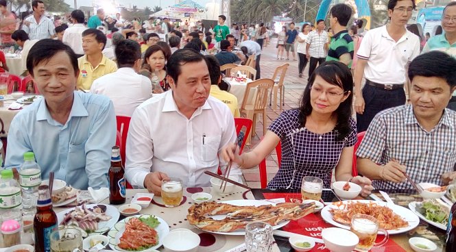 Ông Huỳnh Đức Thơ - Chủ tịch UBND TP Đà Nẵng (áo trắng) cùng lãnh đạo các quận, sở ngành và người dân ăn hải sản tại lễ hội ẩm thực biển chiều tối 1-5 -.Ảnh: Đoàn Cường