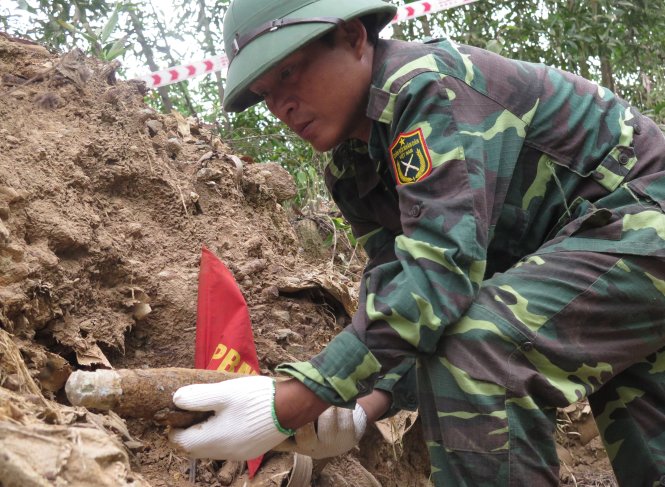 Chiến sĩ công binh moi ra từ lòng đất một quả đạn pháo - Ảnh: Tấn Vũ