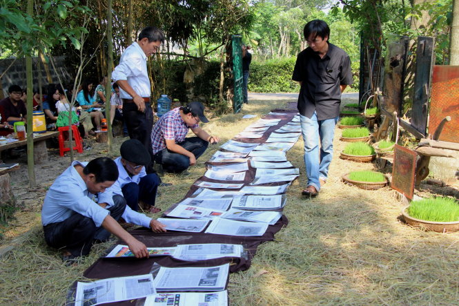 Những bài báo viết về Võ Xuân Huy được bày trên con đường rơm rạ và bà con dân làng ngồi đọc rất say sưa - Ảnh: Minh Tự