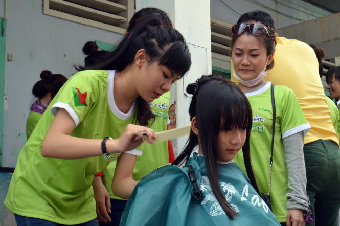 Tình nguyện viên cắt tóc cho các em học sinh - Ảnh: Cẩm Tiên