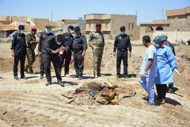 Lực lượng an ninh Iraq cùng nhóm điều tra pháp y đang xem xét hiện trường một ngôi mộ tập thể chứa hàng chục thi thể đàn ông, phụ nữ và trẻ em tại sân vận động ở Ramadi, cách thủ đô Baghdad 115 km về phía tây - Ảnh: AP