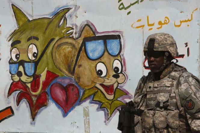 Một người lính Mỹ đi qua bức tường có hình hai nhân vật trong bộ phim hoạt hình nổi tiếng Tom và Jerry tại quận Amil ở thủ đô Baghdad của Iraq - Ảnh: Reuters