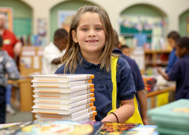 Một em học sinh hớn hở khi được nhận 12 cuốn sách từ Books for Keeps - Ảnh: Booksforkeeps