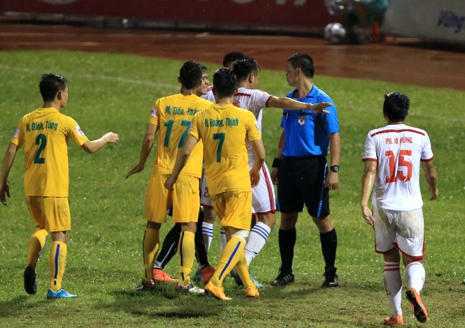 Các cầu thủ SLNA (áo trắng) phản ứng quyết định của trọng tài Hà Anh Chiến. Ảnh: Nam Khánh