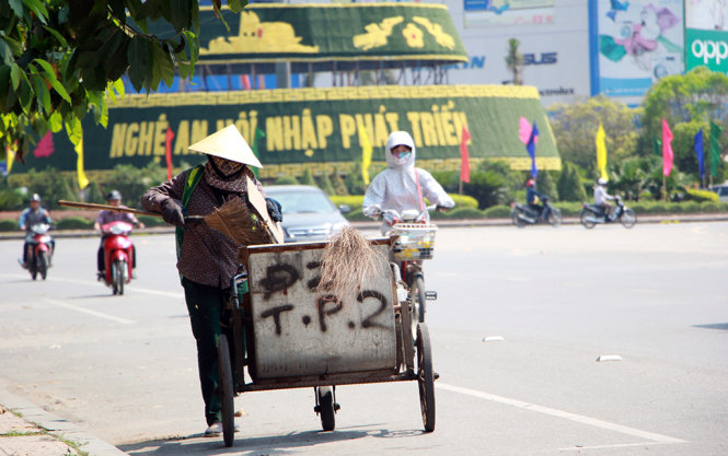 Chị Phạm Thị Lan - công nhân môi trường TP Vinh dọn rác trên tuyến phố Trường Thi, TP Vinh lúc hơn 13g chiều 9-5 - Ảnh: Doãn Hòa