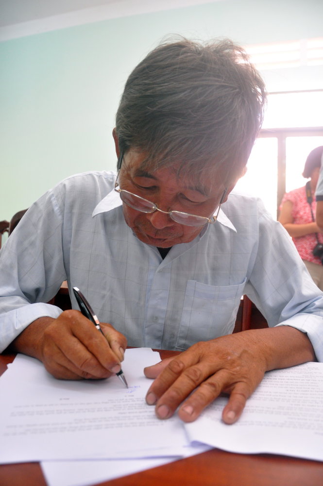 Nông dân Nguyễn Văn An ký vào đơn khởi kiện - Ảnh: Đông Hà