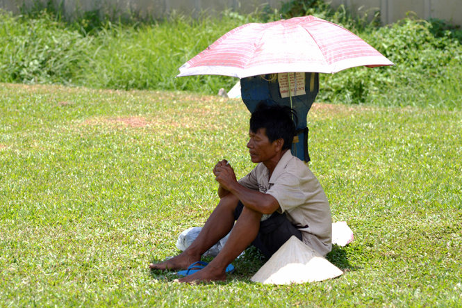 Những người bán hàng lề đường không có bóng mát, tự tạo ra chỗ trú nắng trong những ngày Sài Gòn nóng bức - Ảnh: Duyên Phan