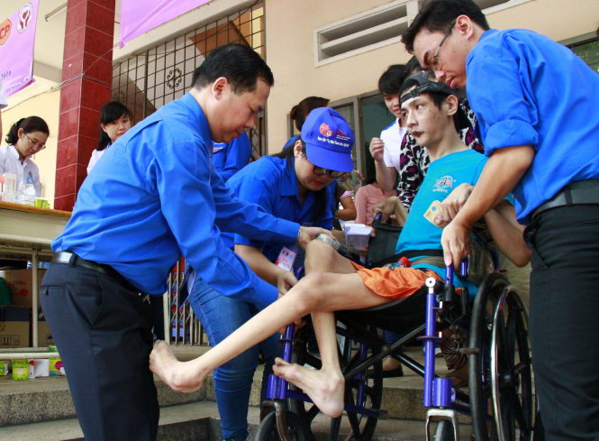Anh Nguyễn Phi Long (bìa trái) cùng các đoàn viên thanh niên giúp một em nhỏ khuyết tật đến khu vực khám bệnh - Ảnh: XUÂN AN