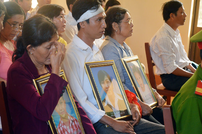 Gia đình chị Vân mang di ảnh của ba mẹ con đến phiên xét xử phiên sơ thẩm - Ảnh: Ngọc Tài