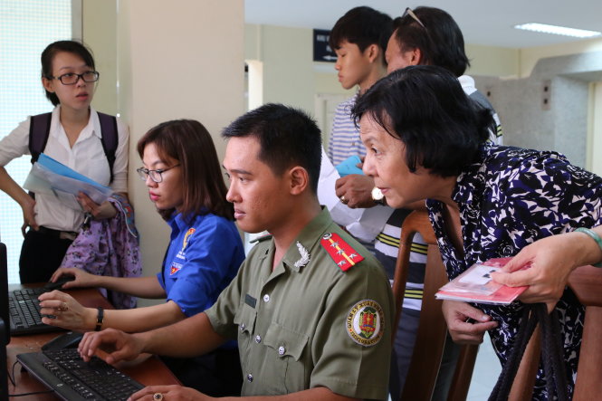 Bà Trần Thị Kim Thu (bìa phải) được cán bộ của PA72 Công an TP.HCM làm tờ khai điện tử giúp tại trụ sở - Ảnh: G.M.