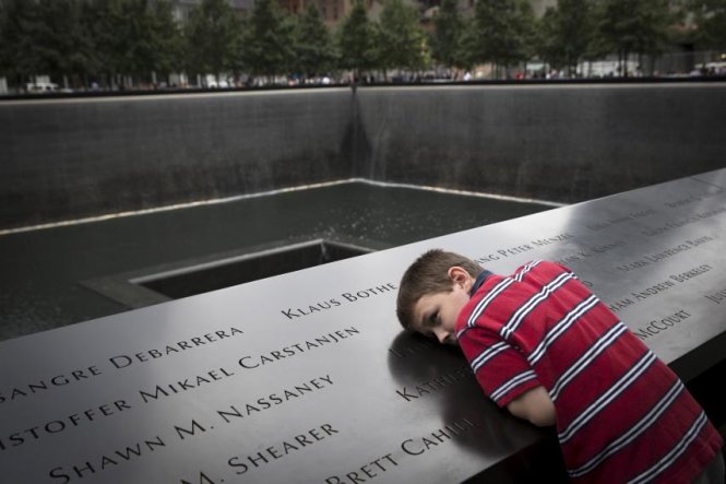 Một em bé nằm trên tấm bia tưởng niệm những nạn nhân thiệt mạng trong vụ khủng bố tấn công vào Trung tâm thương mại thế giới ngày 11-9-2001 tại New York - Ảnh: Reuters