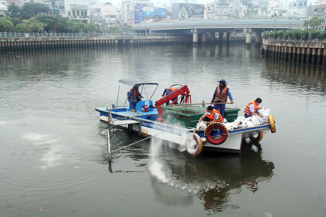 Nhân viên đang rải zeolite cải thiện môi trường kênh Nhiêu Lộc - Thị Nghè