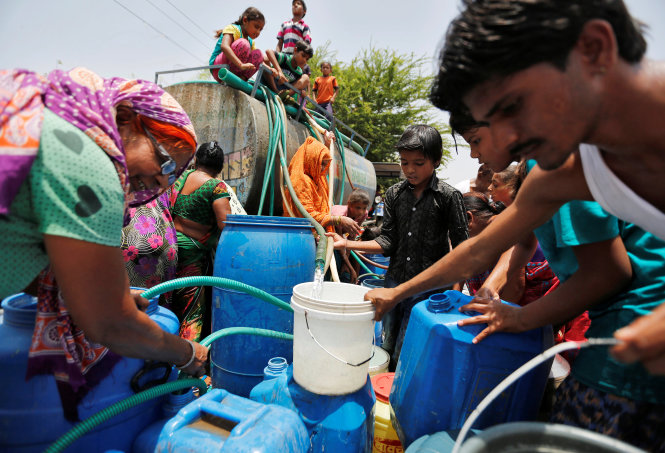 Người dân Ahmedabad, Ấn Độ, tranh thủ lấy nước trong nắng nóng và khô hạn - Ảnh: Reuters