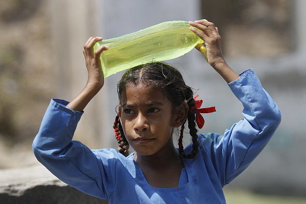Một học sinh Ấn Độ dùng chai nước để xoa dịu cái nóng - Ảnh: AP