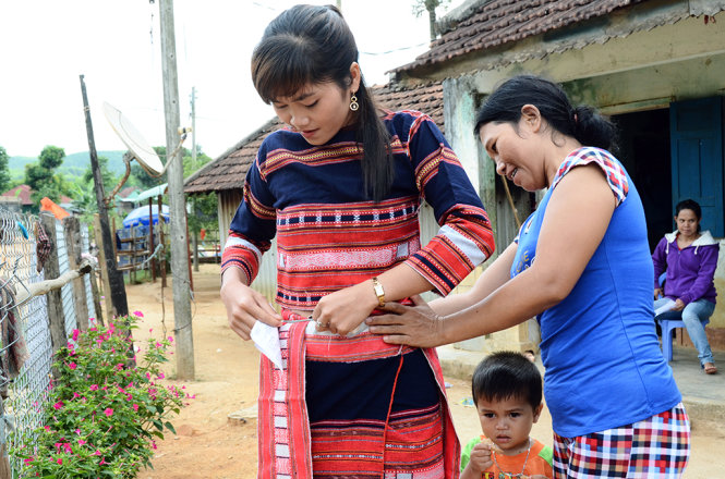 Em Đinh Thị Đốc (sinh năm 1991, làng Hà Giao) lần đầu tiên tham gia bỏ phiếu bầu cử. Em nhờ mẹ giúp chuẩn bị trang phục truyền thống Bana để đến dự lễ khai mạc bầu cử - Ảnh: HOA KHÁ
