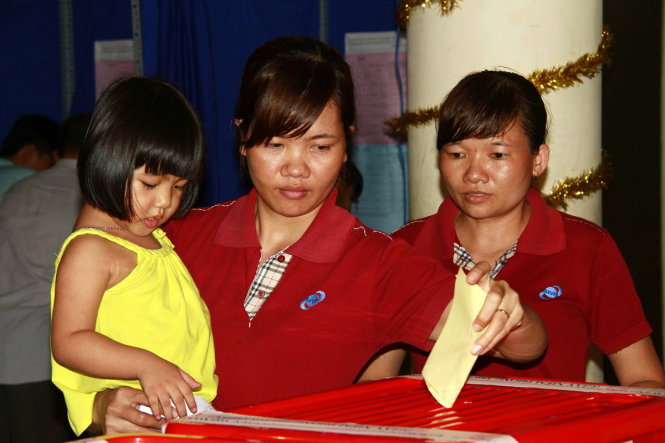 Chị Bàn Thị Hiên (30 tuổi, công nhân công ty MARUEI, KCN VSIP) khi vừa tan ca đêm liền bế con đi bỏ phiếu từ rất sớm - Ảnh: Xuân An