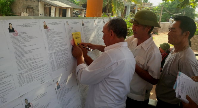 Cử tri tại tổ bầu cử số 3, tại thôn Nhân Quang, xã Nhân Trạch dò từng chữ trên tiểu sử tóm tắt của các đại biểu để lựa chọn cho lá phiếu của mình-ảnh: Quốc Nam
