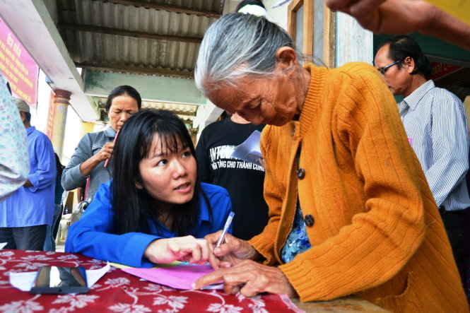 Đoàn viên thanh niên xã Bình Minh hướng dẫn người già ghi phiếu. Ảnh: LÊ TRUNG