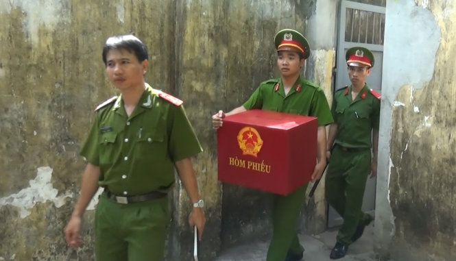 Cán bộ trại trạm giam Hòa Sơn mang thùng phiếu đến tận các buồng tạm giam để cho cử tri bỏ phiếu - Ảnh: HỮU KHÁ