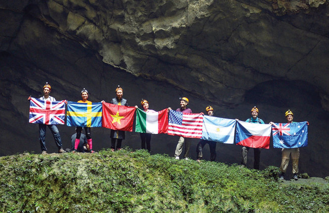 Bảy đại sứ và trợ lý ngoại trưởng Mỹ với lá cờ của quốc gia mình hô vang “Xin chào Việt Nam” từ hố sụt thứ 1 của hang Sơn Đoòng - Ảnh: Thuận Thắng