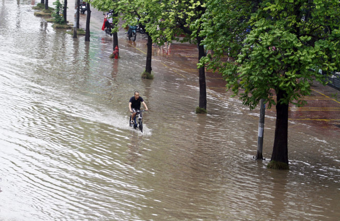 Một người di chuyển bằng xe đạp qua khu vực ngập trên đường Phạm Hùng - Ảnh: NAM TRẦN