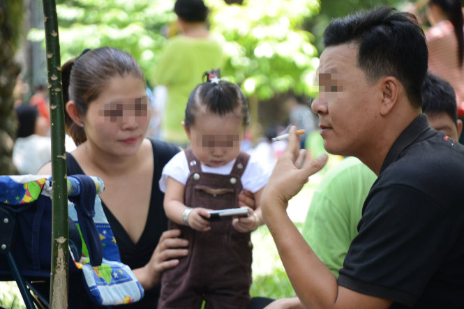 Nhiều người vẫn vô tư hút thuốc lá khi có phụ nữ và trẻ em bên cạnh - Ảnh: Quang Định