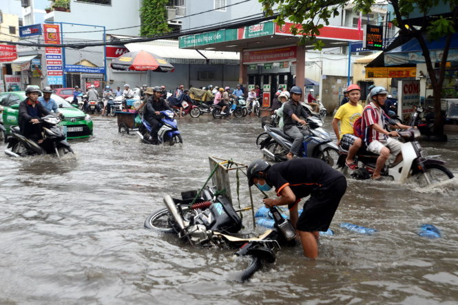 Người dân ngã xe, hàng đổ trôi lềnh bềnh sau khi đường Nguyễn Xí bị ngập nặng trong cơn mưa trưa 18-5- Ảnh: Duyên Phan