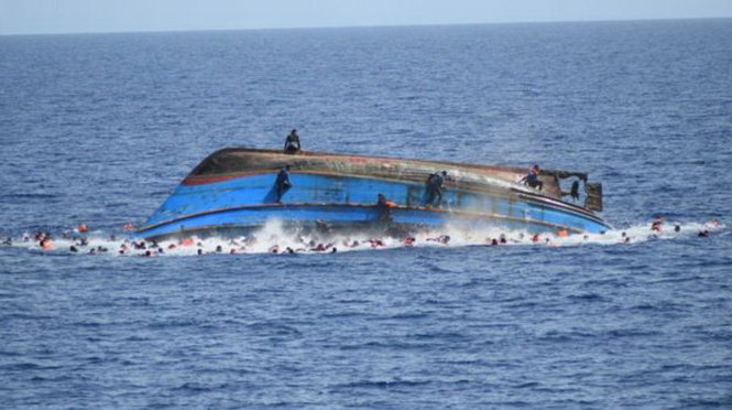 Những người sống sót đang hoảng loạn bám lấy thân tàu sau khi nó bị lật úp giữa biển khơi - Ảnh: EPA/Hải quân Ý