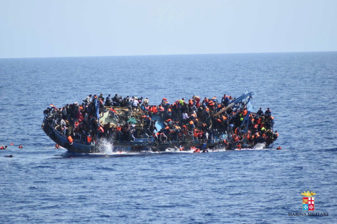 Tấm ảnh ghi hình trực tiếp của hải quân Ý về cảnh tàu người di cư bị lật ngoài khơi Libya. Những người trên tàu mong được cứu nên dồn về một bên khiến tàu lật và làm ít nhất 5 người thiệt mạng. Cảnh tượng này, công bố ngày 25-5, lại khiến dư luận chấn động - Ảnh: Reuters