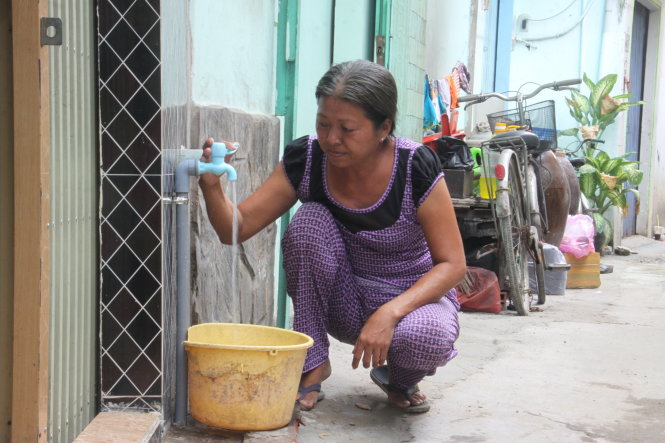 Bà Nguyễn Thị Hạnh lấy nước từ vòi nước mới vừa được lắp đặt trước nhà để sử dụng - Ảnh: Lê Phan