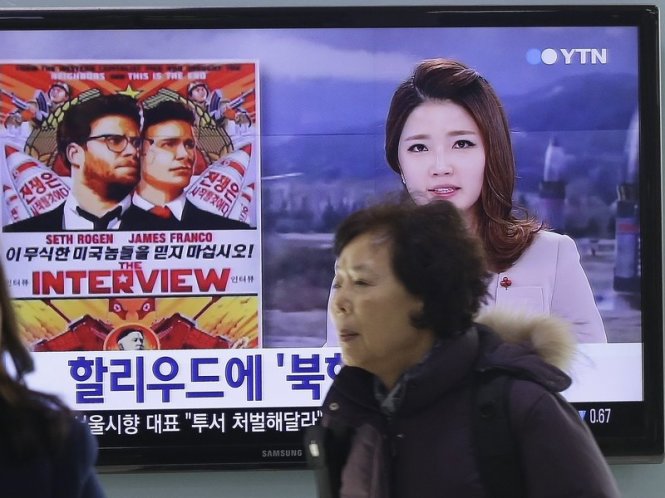 Người dân đi qua màn hình TV có chiếu một poster quảng cáo về bộ phim The Interview của Sony Picture ở nhà ga Seoul, Hàn Quốc - Ảnh: AP