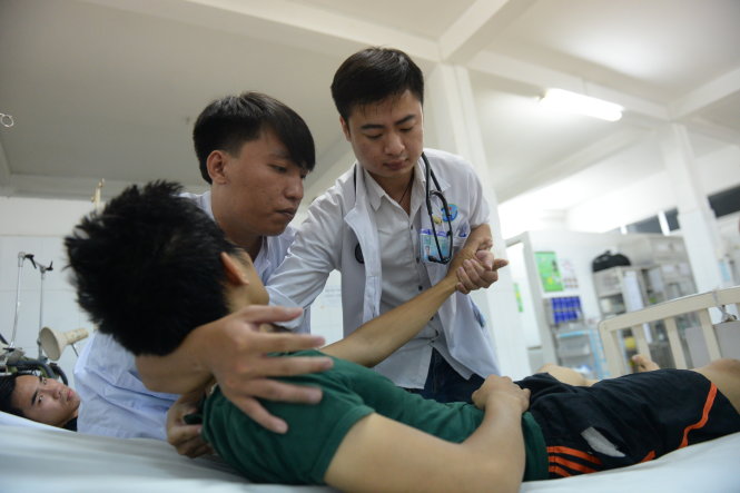 Bác sĩ Minh (phải) điều trị cho bệnh nhân tại khoa cấp cứu Bệnh viện Gò Vấp - Ảnh: HỮU KHOA