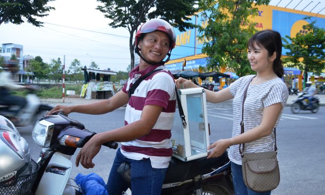 Những lúc rảnh, anh Hoàng Đình Trà lại đeo thùng chạy xe máy xin tiền giúp đỡ từ người dân cho cháu bé mồ côi - Ảnh: L.T.